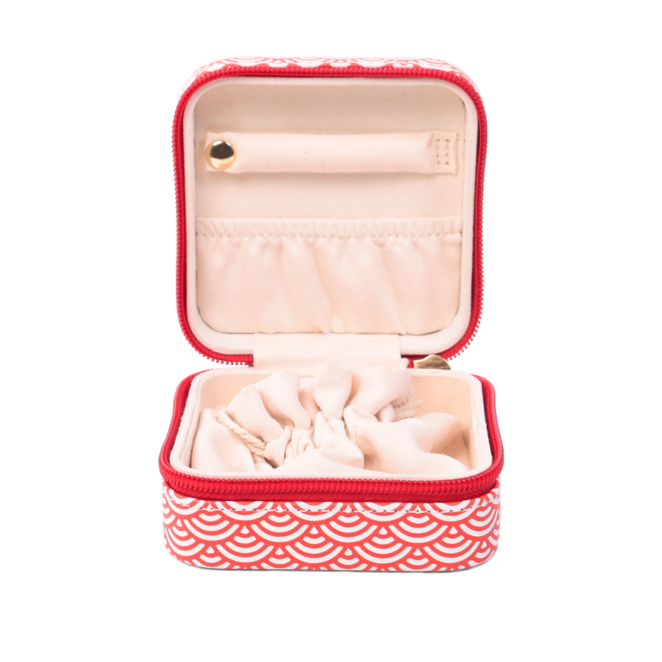 ALT An open square PU leather jewelry box with a red and white geometric print, showing a ring bar and earring holder inside the lid, an inner slip pocket, and a cream-colored drawstring