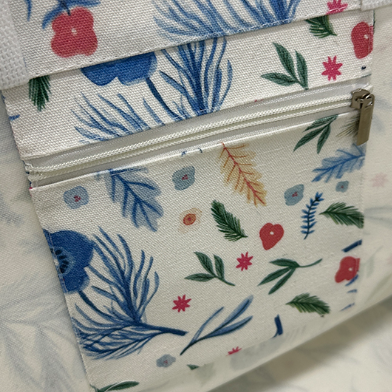 ALT Close-up of the interior of a printed canvas tote bag showing a zippered pouch hanging from the top edge, with a blue floral pattern and a silver zipper pull.