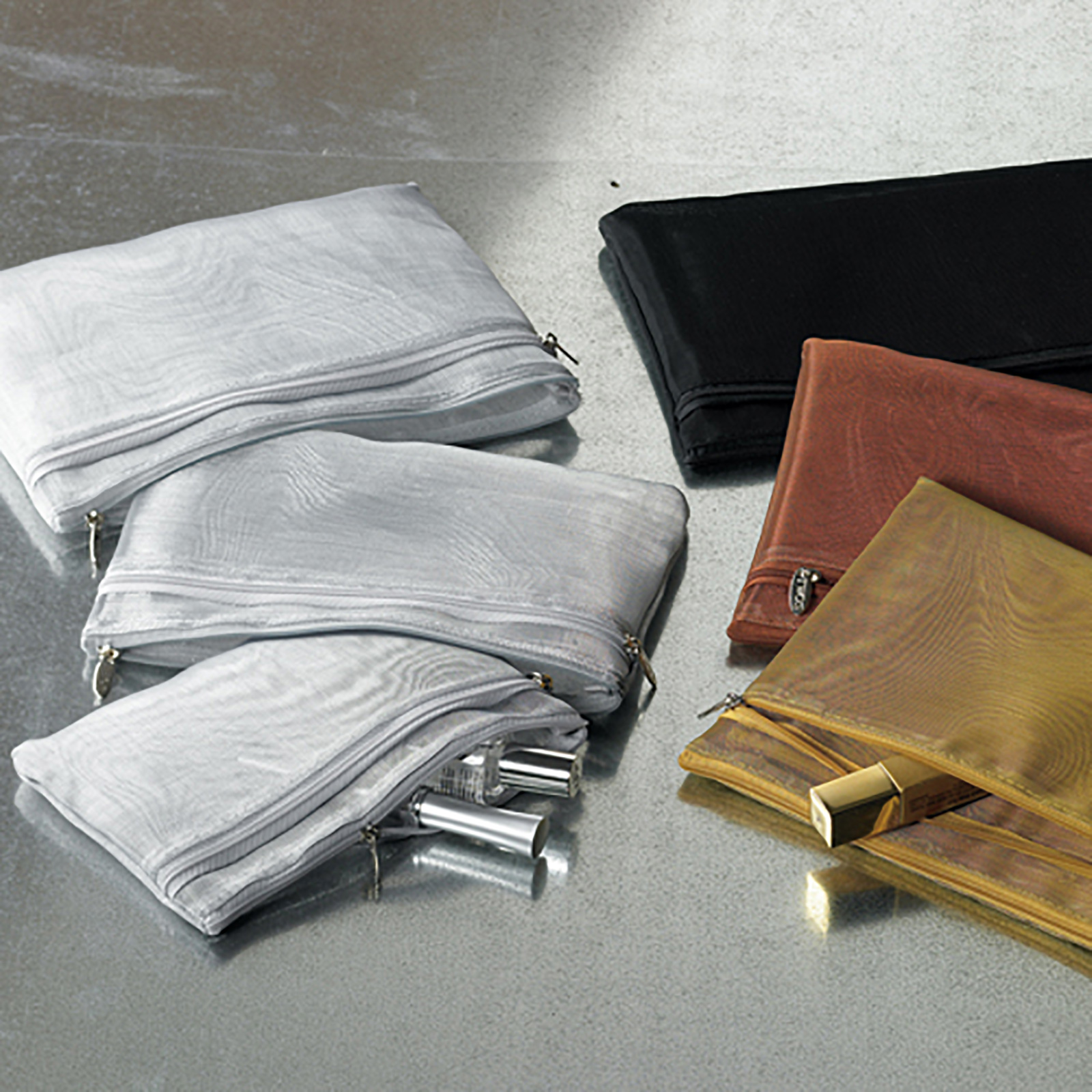 ALT A collection of mesh zipper pouches in silver, black, brown, and gold, arranged on a grey surface, with a silver cosmetic tube and a gold lipstick visible inside the pouches