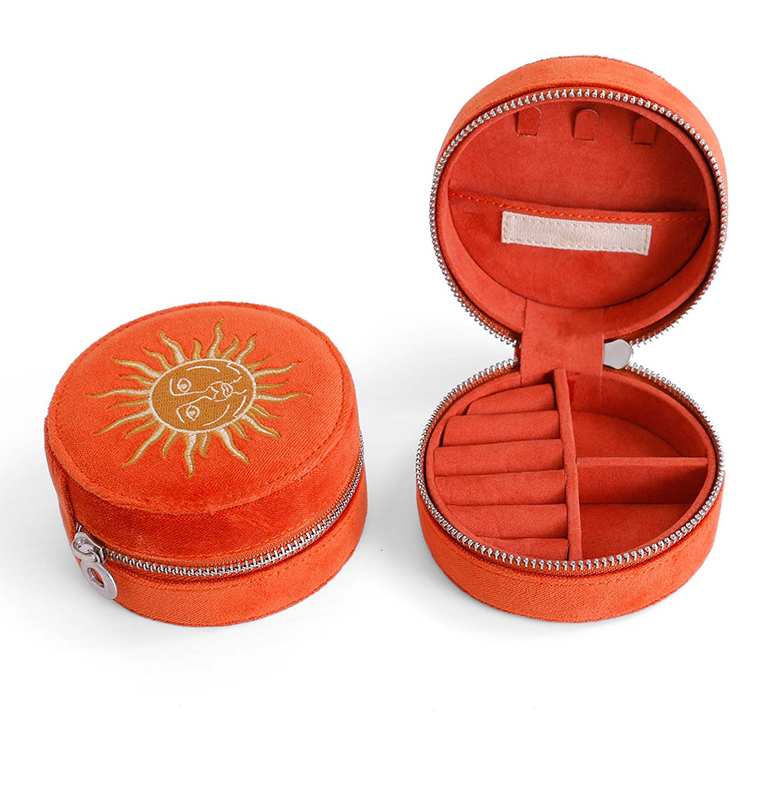 ALT A round orange velvet jewelry box with floral leaf embroidery on the lid, shown open to reveal a soft velvet interior with a zipper closure.